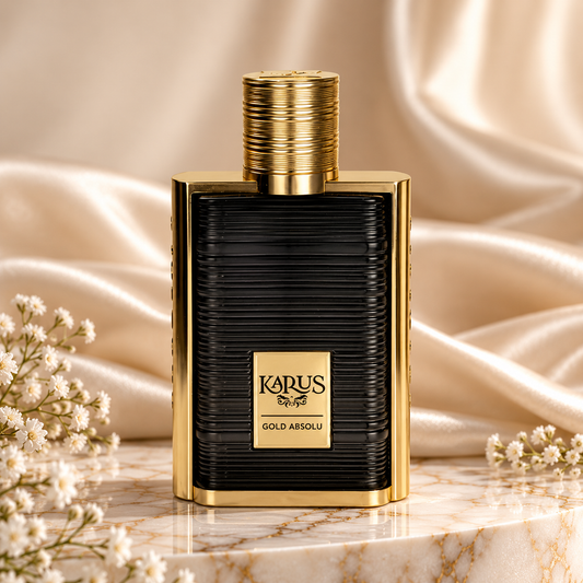 Frasco preto texturado de Karus Gold Absolu Khadlaj, com moldura e tampa douradas, sobre uma base de mármore, com tecido acetinado bege e pequenas flores brancas ao redor.