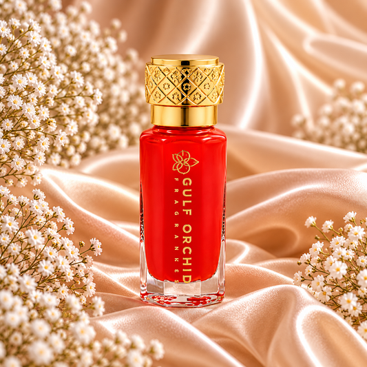 Frasco de Pomegranate Musk Collection Perfume Oil 12 mL da Gulf Orchid, com corpo vermelho, letras douradas e tampa dourada trabalhada, entre cetim e flores brancas.